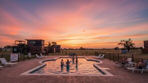 A swimming pool with lounge chairs and a building in the background. - Wine Trail Cottage · Hot Tub, Pool & Wineries (Fredericksburg)