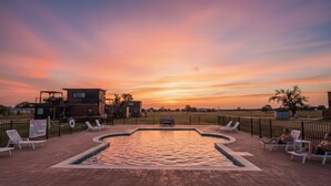 Ein Poolbereich mit Liegestühlen und Blick auf den Sonnenuntergang.