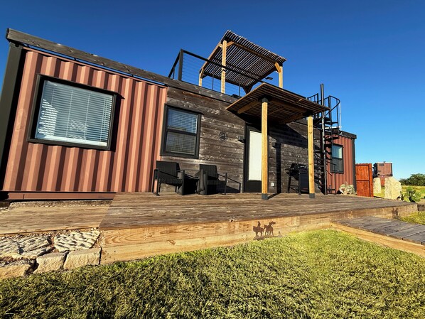 A modern house with a wooden deck, outdoor seating, and a pergola. - Wine Country Container, Rooftop Fire Pit & Pool (Fredericksburg)