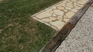 Un edifici modern amb un camí de pedra que condueix a una terrassa de fusta.