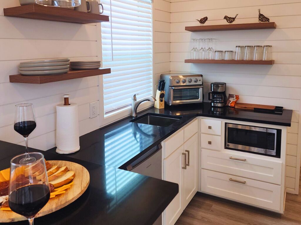A modern kitchen with white cabinetry, a black countertop, and built-in appliances including an oven and a coffee maker.