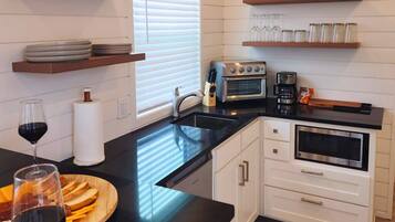 A modern kitchen with white cabinetry, a black countertop, and built-in appliances including an oven and a coffee maker.
