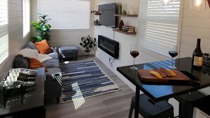 Une cuisine moderne avec un coin repas, comprenant un téléviseur, un verre à vin et une bouteille posés sur le comptoir.