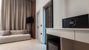A modern living room with a sofa, a television mounted on the wall, and a security keypad on the counter. - Marbella Sol (Ksamil)
