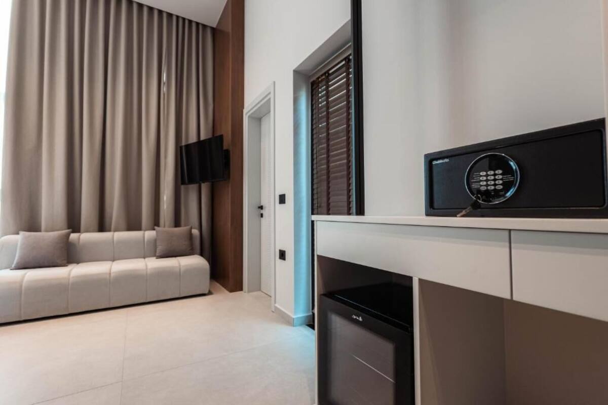 Una sala de estar moderna con un sofá, un televisor montado en la pared y un panel de control de seguridad en la encimera.