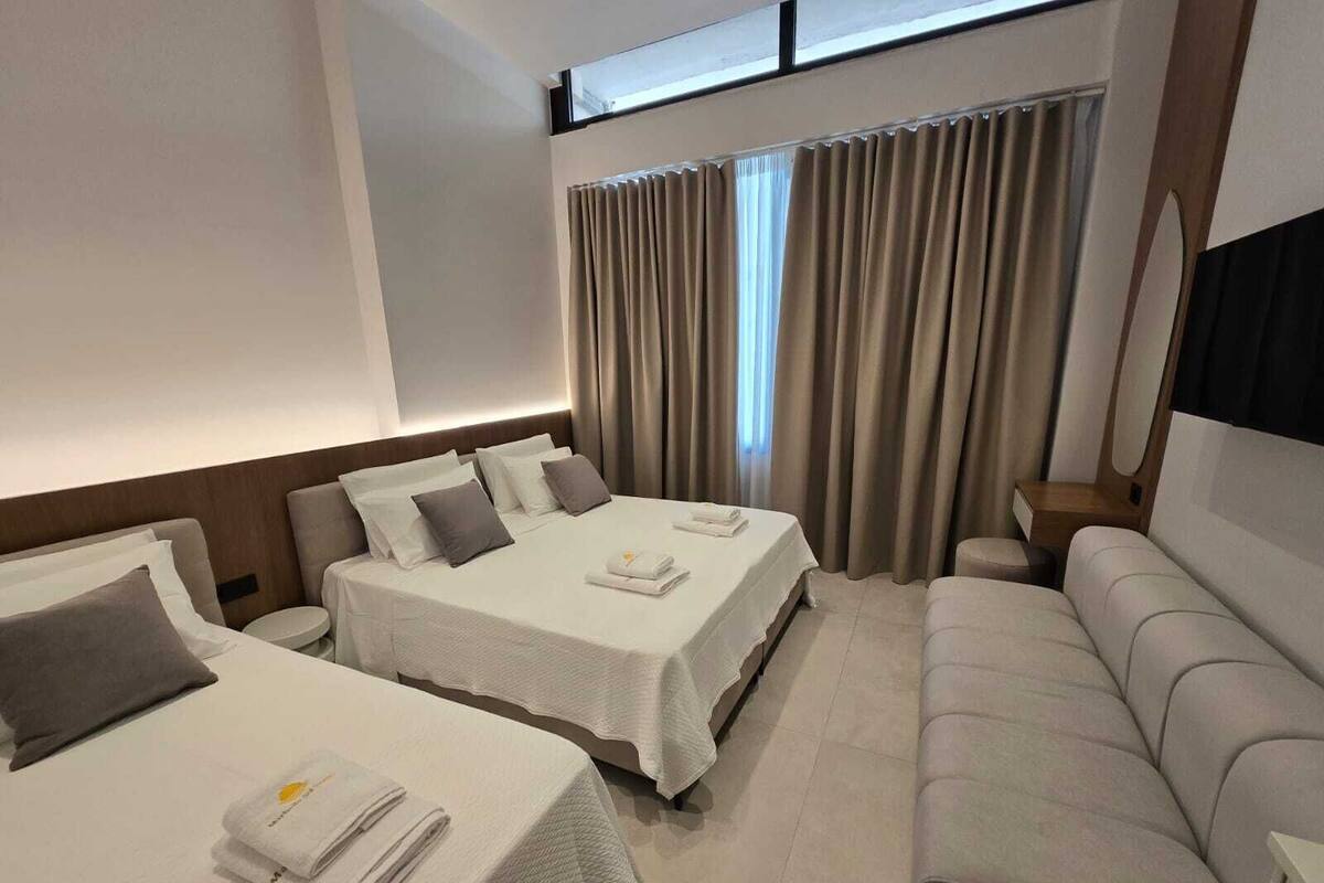 Una habitación de hotel con dos camas, un sofá y un televisor.