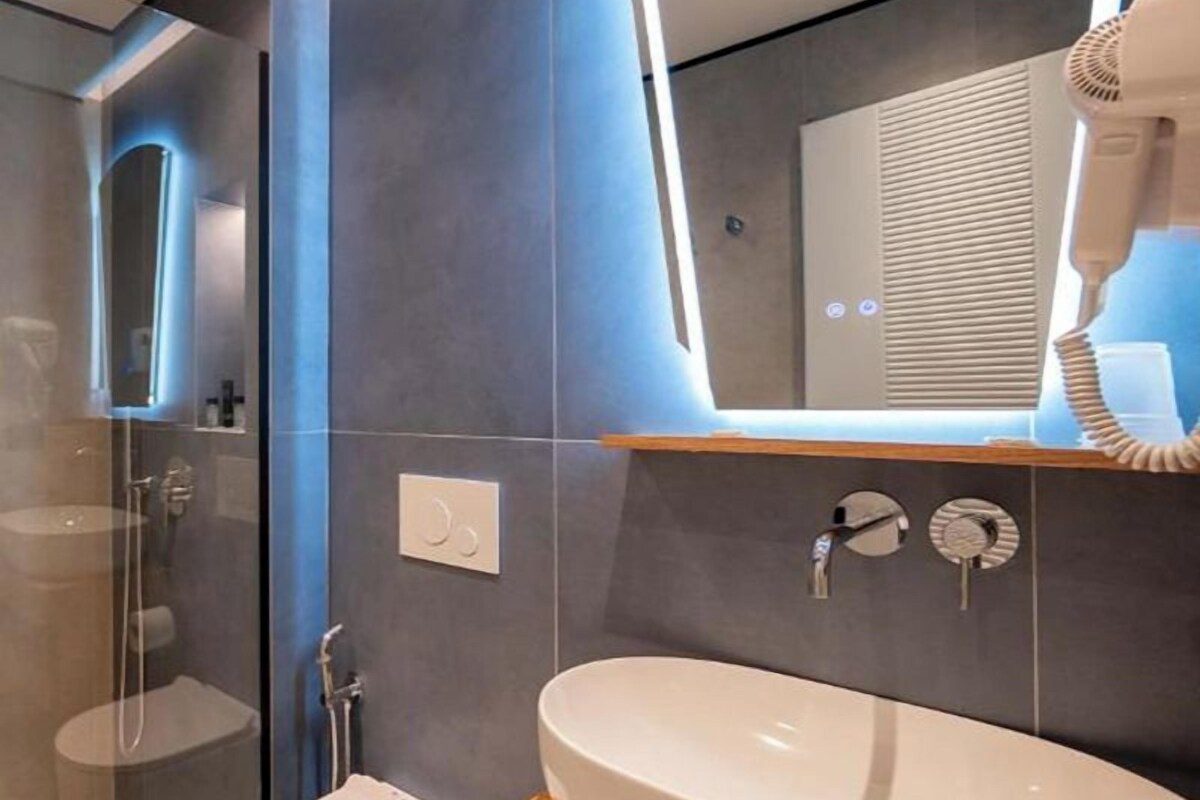 A modern bathroom with a glass shower enclosure, a white toilet, and a large sink with a wooden countertop.