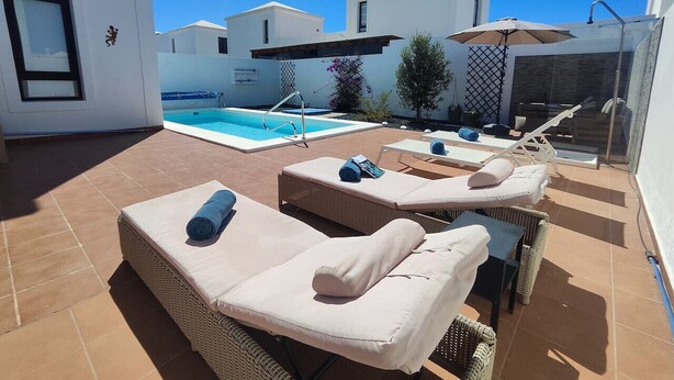 Un espace piscine aménagé sur le toit, avec des chaises longues et une piscine.