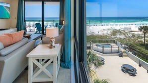 Un balcon avec vue sur la plage, un canapé, une table et un espace piscine.
