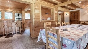 A wooden cabin with a dining area featuring heart-shaped chairs and a table covered with a patterned tablecloth. - Family chalet in Saint-Gervais, 6 bdr, 12 pax, WiFi, parking (Saint-Gervais-les-Bains)