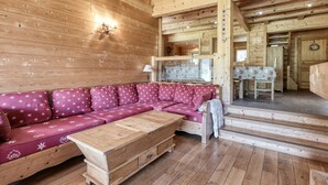 A wooden cabin interior with a sofa, a wooden chest, and a dining area. - Family chalet in Saint-Gervais, 6 bdr, 12 pax, WiFi, parking (Saint-Gervais-les-Bains)