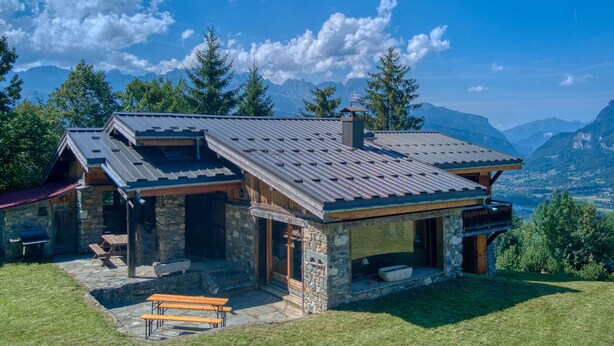 A stone house with a sloped roof, wooden deck, and a bench. - Family chalet in Saint-Gervais, 6 bdr, 12 pax, WiFi, parking (Saint-Gervais-les-Bains)