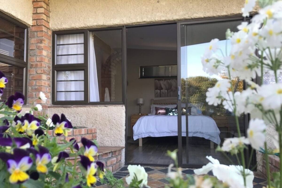 Un dormitorio con cama, mesita de noche y ventana con cortinas.