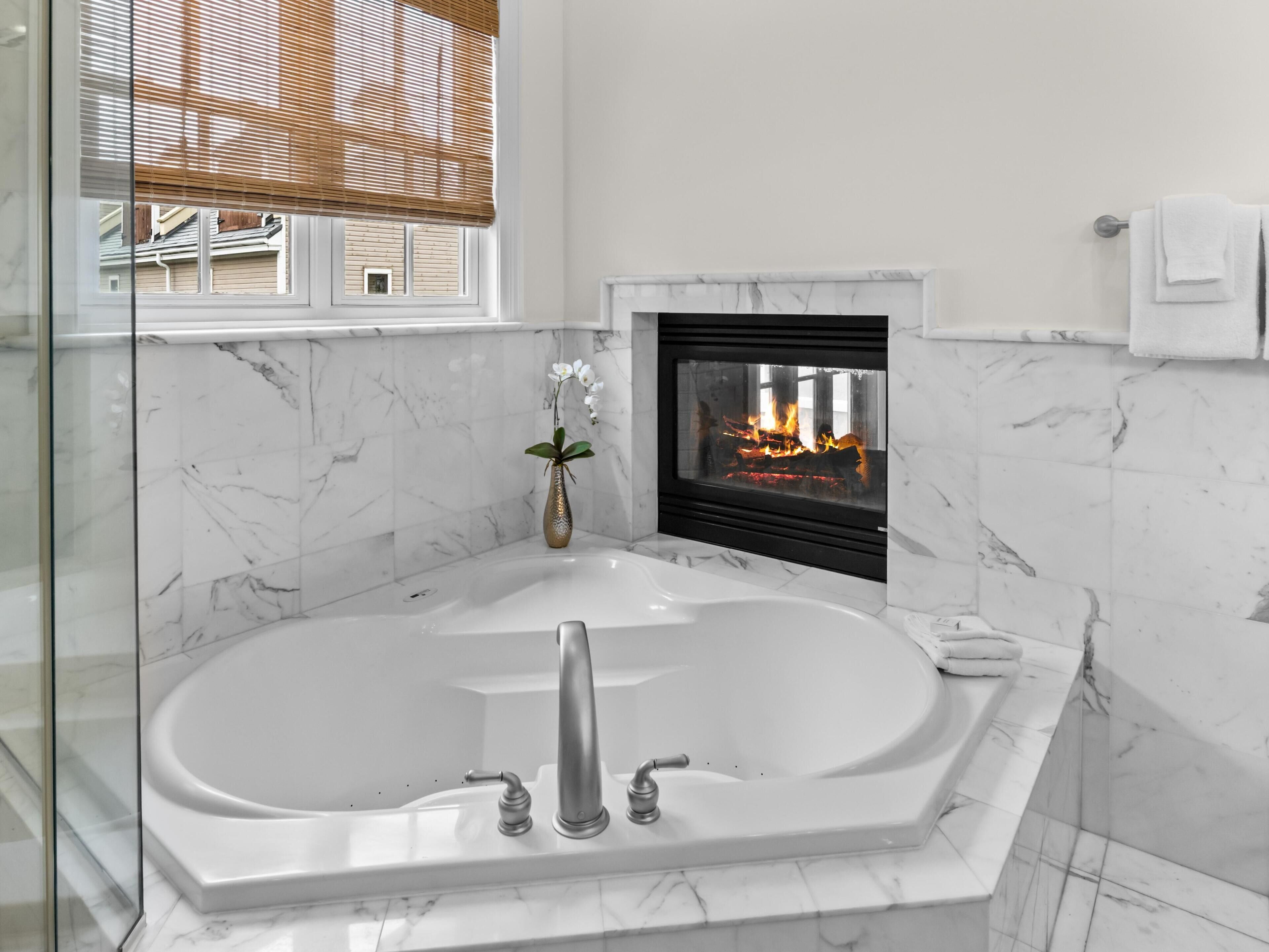 Ein modernes Badezimmer mit einer freistehenden Badewanne, einer Duschkabine aus Glas und einem Kamin.