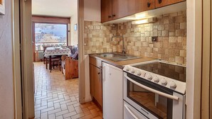 Une cuisine de taille réduite, équipée d’une cuisinière, d’un four et d’un crédence carrelée.