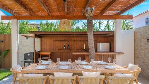 Un espace de restauration en plein air avec une table en bois prévue pour six personnes, entourée de chaises en osier.