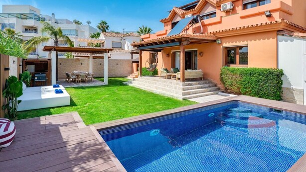 Une maison moderne dotée d’une piscine, d’un patio et d’un espace extérieur aménagé et couvert.