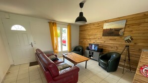 A living room with a red sofa, a wooden coffee table, a television, and a lamp. - 3-Bedroom House with Terrace and Garden in La Terrière (La Tranche-sur-Mer)