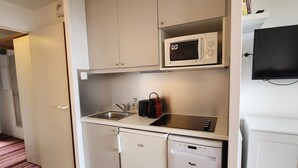Een kleine keuken met een magnetron, spoelbak en vaatwasser.
