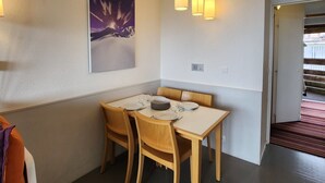 Een eetruimte met een gedekte tafel voor twee personen, een schilderij aan de muur en hanglampen erboven.