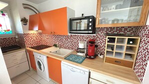 A compact kitchen with a microwave, coffee maker, and a washing machine.