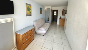 A hallway with a beige sofa, wooden cabinet, and artwork on the walls.