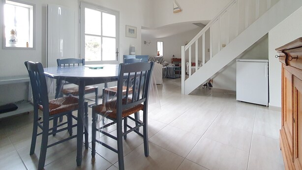 Un amplio salón con una mesa de comedor, sillas, un sofá y una escalera.