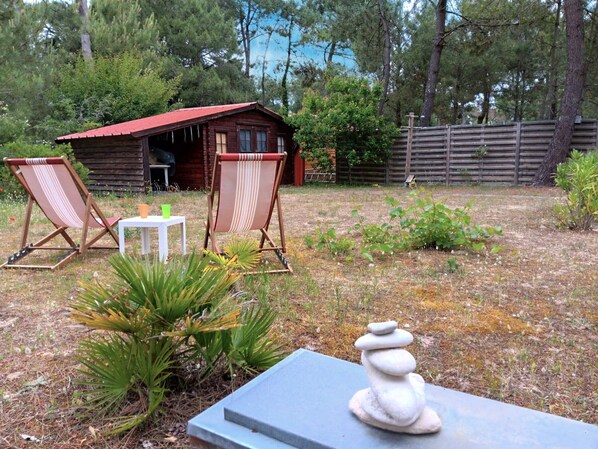 Een rustieke hut met twee strandstoelen en een kleine tafel in de voortuin.