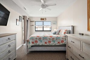 Quarto com cama, penteadeira e ventilador de teto.