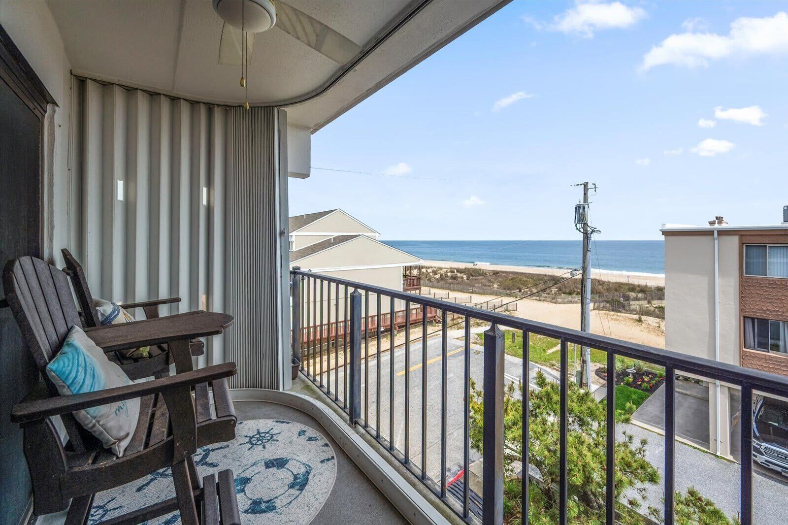 Een balkon met een stoel, een kleedje en uitzicht op het strand en de oceaan.