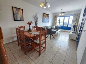 Un comedor con una mesa y sillas de madera, un sofá y un ventanal con cortinas.