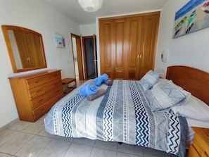 Un dormitorio con cama, armario de madera y espejo.