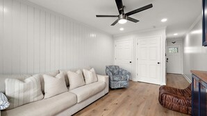 Ein modernes Wohnzimmer mit einer Couch, einem gemusterten Sessel und einem Deckenventilator.