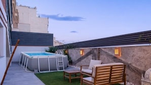 En takterrass med en bubbelpool, utemöbler och en mur av sten.