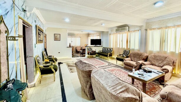 A spacious living room with a marble floor, a large sofa set, a television, and a fan. - Cozy apartment in tranquil Old Cairo with fitness room, WiFi (Egypt)
