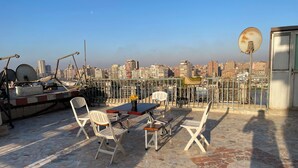 A rooftop terrace with a table and chairs, a satellite dish, and a cityscape view. - Cozy apartment in tranquil Old Cairo with fitness room, WiFi (Egypt)