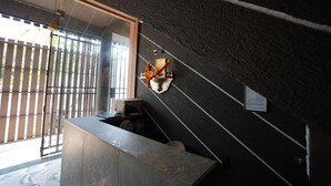 Zona de recepción con una pared oscura y texturizada, un mostrador de recepción y un gran ventanal con vistas al exterior.