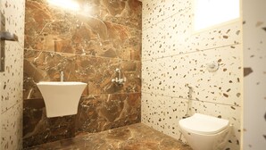 Un baño con lavamanos de mármol, inodoro y pared con diseño moteado.