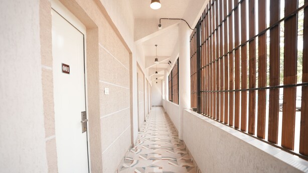 Un pasillo con piso estampado, una puerta con la etiqueta '001' y una ventana con barrotes verticales.