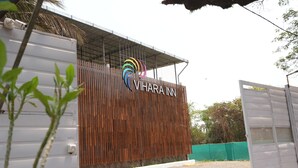 Entrada de un hotel con fachada de madera y un logotipo colorido.