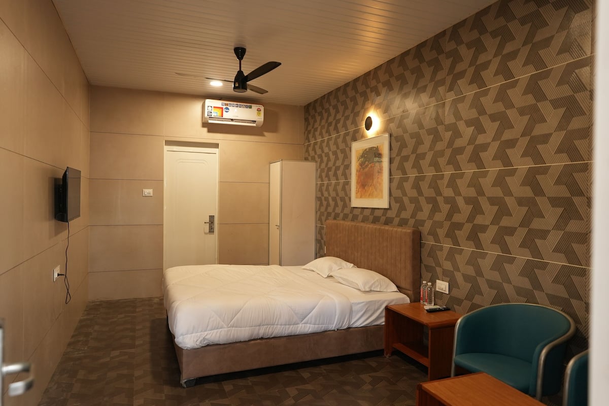 Ein Hotelzimmer mit Bett, Schreibtisch, Stuhl, Deckenventilator und Klimaanlage.