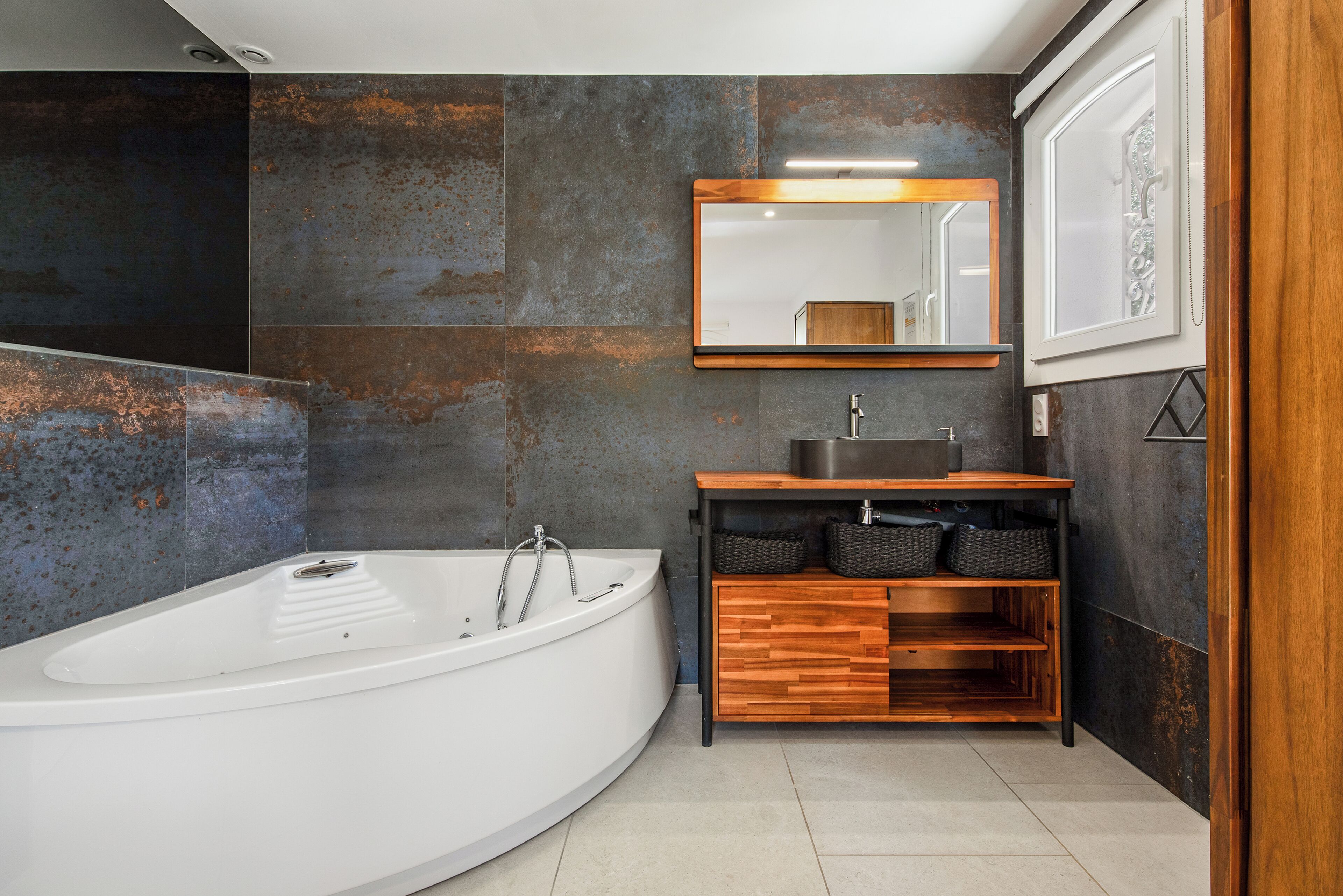 A modern bathroom with a freestanding bathtub, a wooden vanity with a sink, and a large mirror above the vanity.