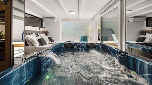 A modern interior with a hot tub, a bed with pillows, and a bathroom with a shower. - VILLA RASOA (Agde)