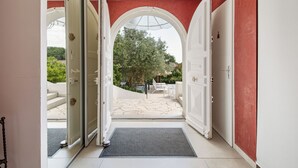 A hallway with open doors leading to a patio area with outdoor furniture and a view of trees. - VILLA RASOA (Agde)