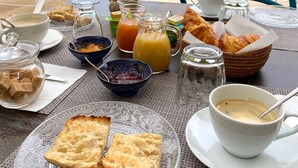 A breakfast setup with croissants, bread, coffee, and juice by a poolside. - VILLA RASOA (Agde)