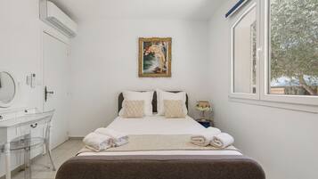 Un dormitorio con cama, mesita de noche, espejo y ventana.
