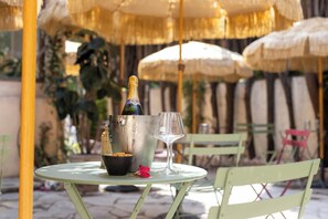A table with a bottle of champagne, a glass, and a bowl of snacks. - Hôtel Lou Juan (Antibes)