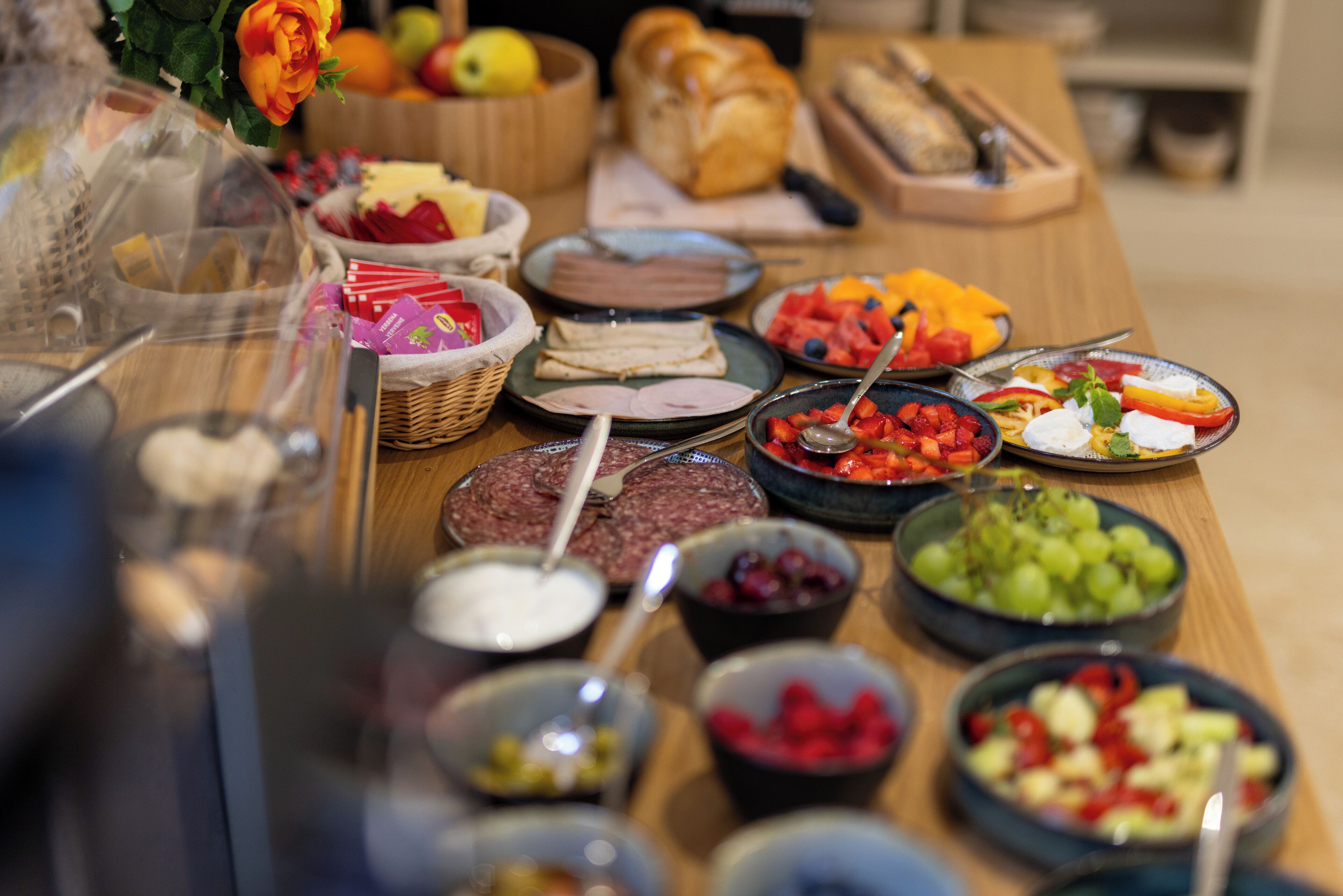 A buffet table with various food items including meats, fruits, and vegetables.