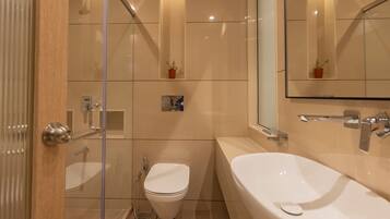 Un baño moderno con cabina de ducha de vidrio, inodoro y bañera independiente.