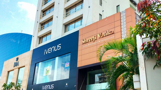 A multi-story building with a modern design, featuring a prominent 'iVenus' sign and a 'Shreeji Vatik' sign indicating a banquet and party venue. - Hotel Shreeji Vatika-Airport Road (Surat)
